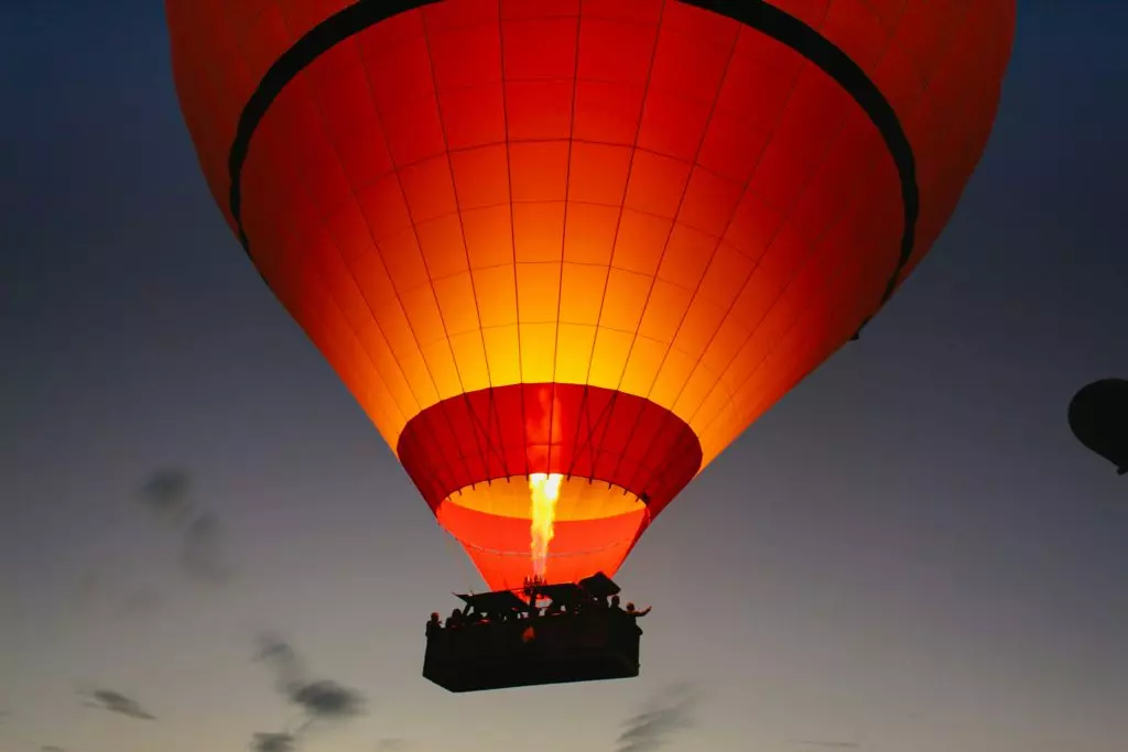 Une grande flamme illumine un mongolfiere qui lance son ascencsion dans le ciel